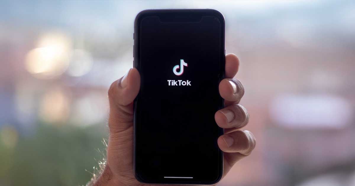 Logo TikTok pe ecranul unui telefon mobil, birou guvernamental american, iulie 2026, decizie Departamentul Justiției