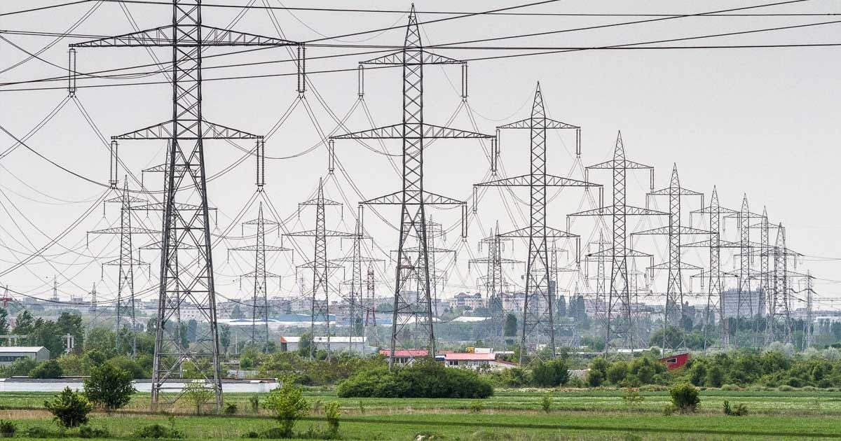 Stâlpi de înaltă tensiune și linii electrice pe fondul unui cer înnorat, simbol al crizei energetice din România, 2026