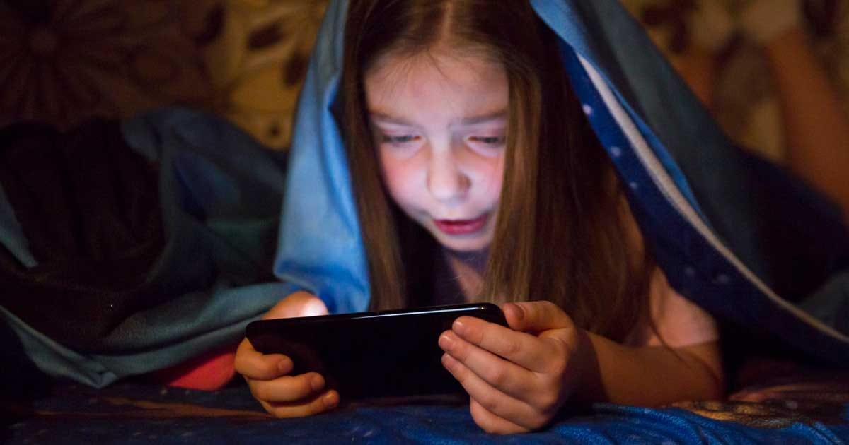 Copil folosind un telefon mobil, context despre propunerea europeană de interzicere a rețelelor sociale pentru minori, septembrie 2026